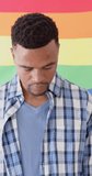 Vertical video of portrait of happy african american man holding lgbt rainbow flag, slow motion. Pride, love and tolerance.
