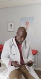 Vertical video of portrait of african american male doctor using tablet, slow motion. Medical staff, medicine, communication and healthcare.