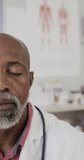Vertical video of portrait of african american male doctor smiling, slow motion. Medical staff, medicine and healthcare.