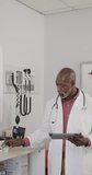 Vertical video of portrait of african american male doctor using tablet, slow motion. Medical staff, medicine, communication and healthcare.