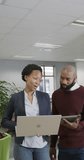 Vertical video of happy african american business people using laptop in slow motion. Global business, finances and office concept.