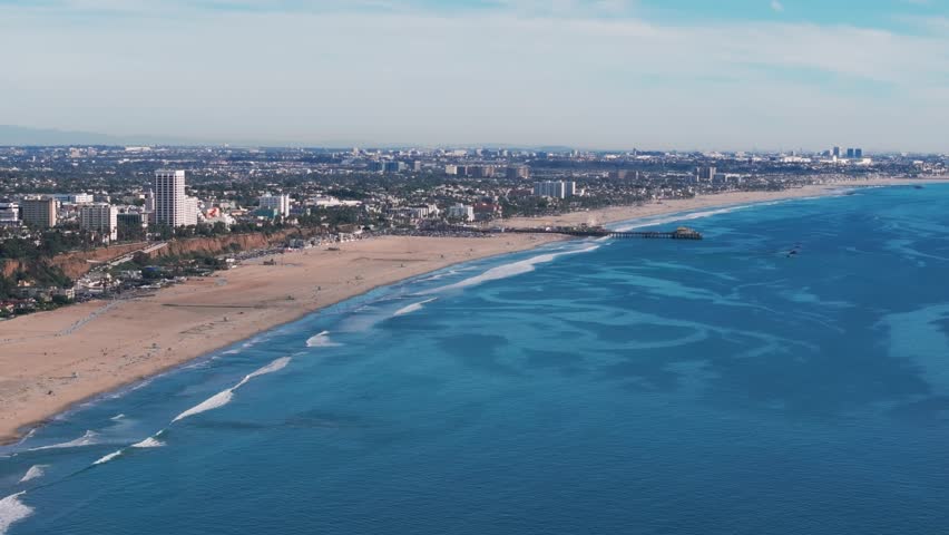 Drone shot panning to the right overlooking the santa monica beach and pier