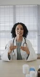 Vertical video of biracial female doctor having video call, slow motion. Medical staff, medicine, communication and healthcare.