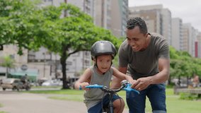 Happy latin father helping smiling boy to ride bike on cityu park. Happy latin child and young dad riding bike. Smiling daddy teaching son to ride a balance bicycle.
 - Powered by Shutterstock - Get 15% off with code: PIKWIZARD15