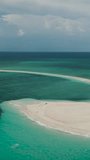 Aerial view of white sandbar surrounded by azure sea water texture in Camiguin, Philippines. Vertical video.