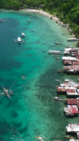 Traditional fishing boats floating over the blue sea, stilt house in coastline of Samal Island, Davao. Philippines. Vertical view.
