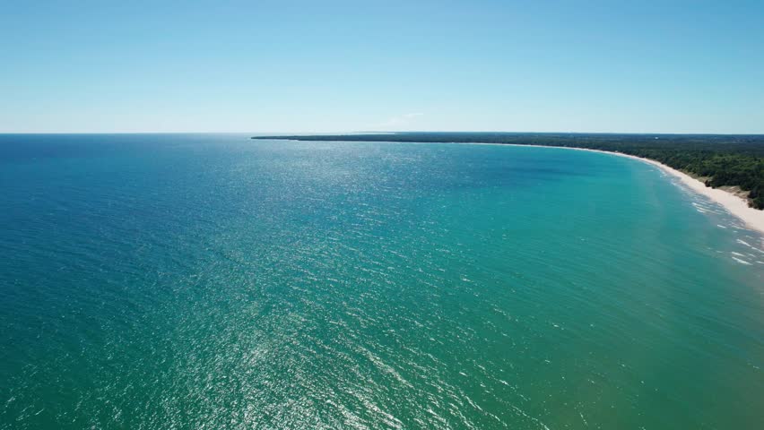Beautiful drone shot panning to the right of the colorful waters of lake Michigan