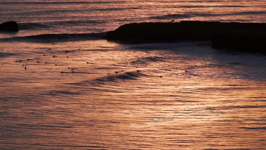 Sunset reflection on the pacific ocean in California with surfers and waves