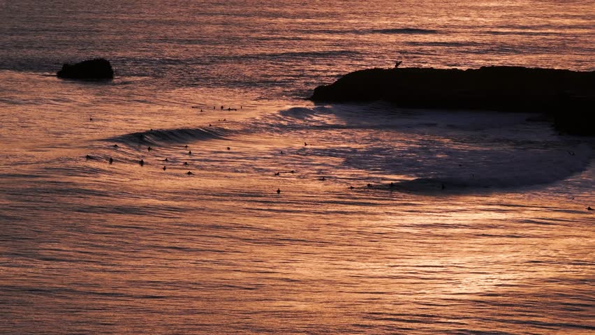 Drone aerial view of sunset in Santa Cruz, California with surfers catching waves