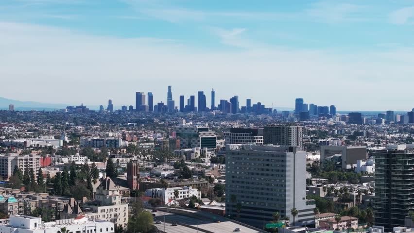 Telephoto drone shot of the los angeles skyline during a sunny day panning left