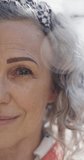 Vertical video portrait of happy senior caucasian woman looking at camera and smiling, slow motion. Retirement, domestic life and lifestyle.
