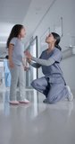 Vertical video of biracial female surgeon high fiving with girl in hospital in slow motion. Medicine, health and care.