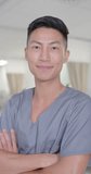 Vertical video of portrait of happy asian male nurse looking at camera, in slow motion. Hospital, medicine and healthcare.