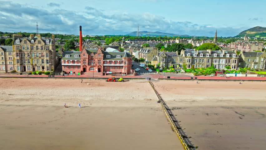 Aerial view of Portobello Beach, traditional seaside pursuits on the prom with sandy stretches of beach overlooking the Forth. Beach next to Edinburgh features a promenade with historical buildings.