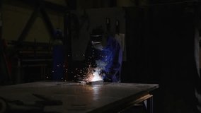 Motion shot of worker welding metal in a factory. Employment and industry concept.