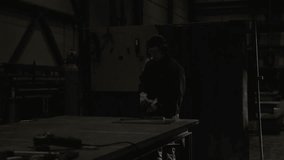 Dark cinematic scene of worker cutting metal and throwing spark. Employment and labor concept