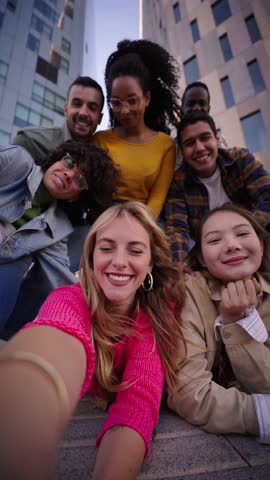 Vertical. A group of happy people is sharing a fun moment. Young friends take a selfie picture during a leisure event. The team is traveling together. Smiling community portrait looking at camera Royalty-Free Stock Footage #3456259825