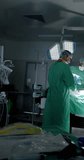 Vertical video of diverse surgeons with face masks during surgery in slow motion. Medicine, health and care.