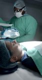 Vertical video of diverse surgeons with face masks using oxygen mask on patient in slow motion. Medicine, health and care.