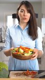 Beautiful young woman streaming broadcast video blog about tasty and healthy food at the home kitchen using her smartphone
