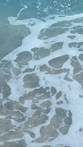 Ocean waves crashing on the beach with sand in the mixture in slow motion vertical video for social media Royalty-Free Stock Footage #3456329739