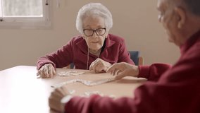 Senior people playing dominoes patiently in a nursing home