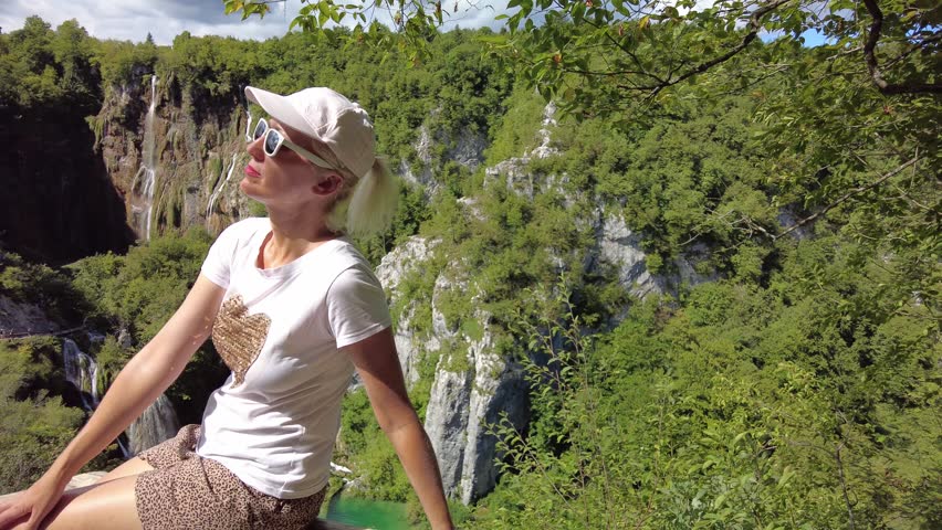 girl sitting on viewpoint the Plitvice Lakes National Park of Croatia. Sastavci and Veliki Slap waterfalls in Lika region. UNESCO World Heritage of Croatia named Plitvicka Jezera.