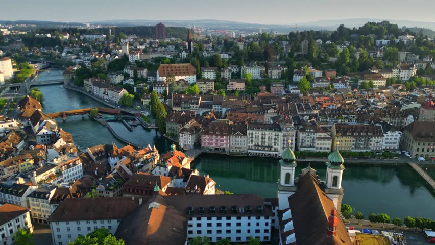Aerial morning view of Lucerne old town and Reuss river. View of Jesuitenkirche Hl. Franz Xaver church and old houses in Luzern city center, Switzerland, shot at sunrise Royalty-Free Stock Footage #3456481287