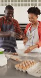 Vertical video of happy african american couple baking together. Love, relationship and spending quality time together concept.