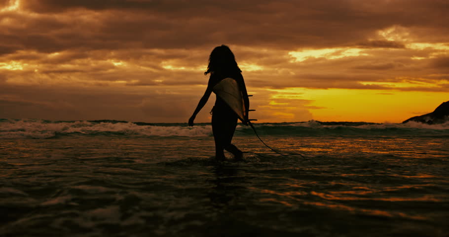 Sunset, silhouette and woman with a surfboard, seaside and water with adventure and vacation. Person, girl and surfer with ocean or beach with shaka sign and summer with nature or travel with journey