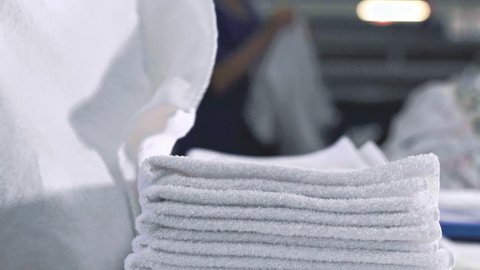 Women folding fresh towels in a a laundry 
