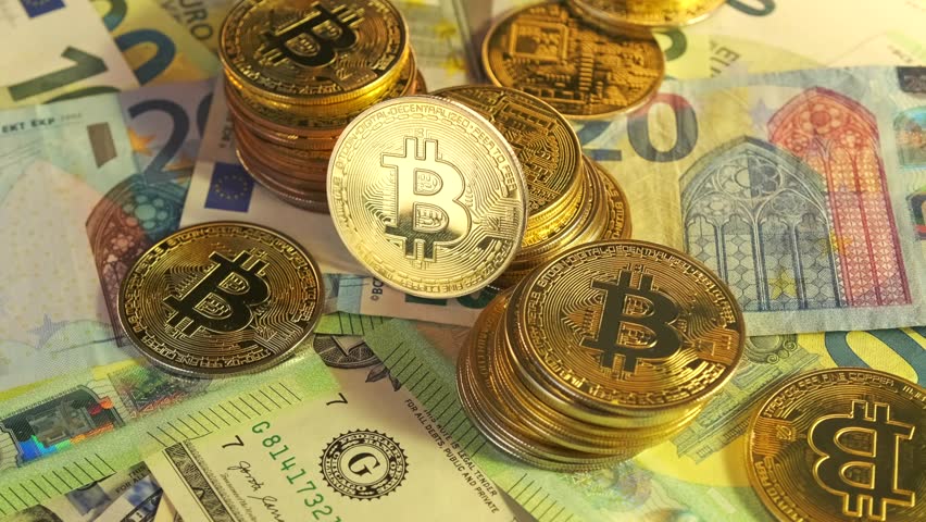 Rotating bitcoin gold coins stacks lies on euro and dollars different denomination background close-up. Virtual and physical currency and global economy .