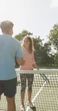 Vertical video of happy biracial woman and man with tennis rackets. Sport, active lifestyle and tennis training concept.