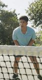 Vertical video of focused biracial man playing tennis. Sport, active lifestyle and tennis training concept.