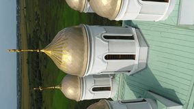 Vertical video. Svyatogorsky Assumption Zymna Stauropean Monastery. Flying around the gilded domes of the church. Aerial view Village Zymne.