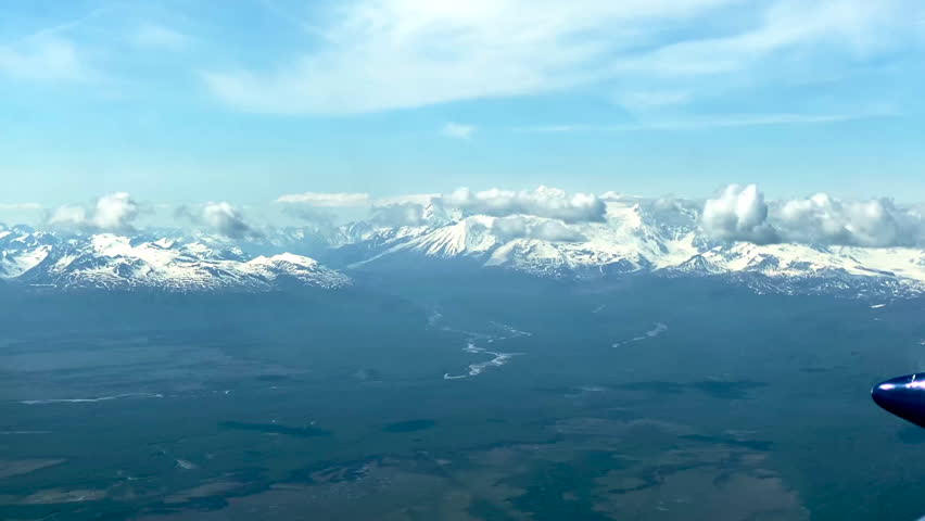 Beechcraft Bonanza airplane wingtip flies over Lake Clark Pass in Alaska. Mount Redoubt in the background. Small aircraft are only way to see many areas of Alaska.
