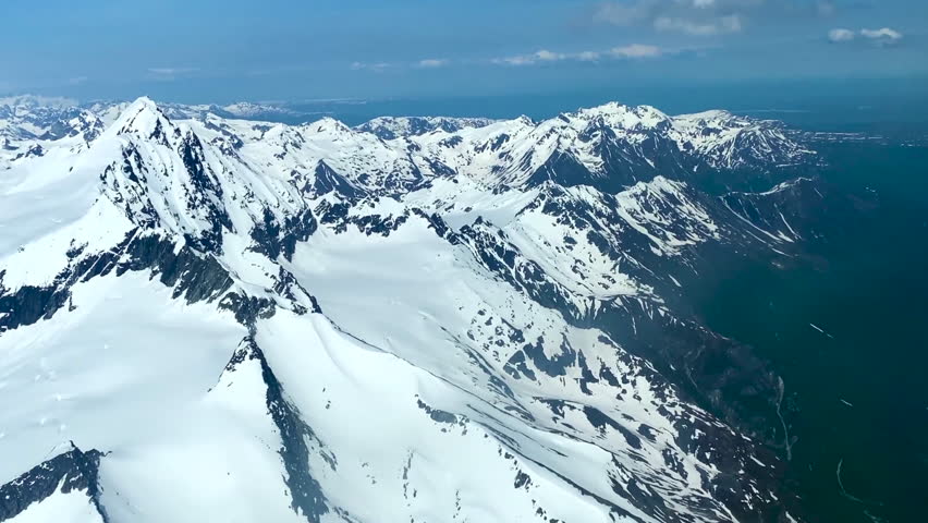 Beechcraft Bonanza airplane wingtip flies over Lake Clark Pass in Alaska. Mount Redoubt in the background. Small aircraft are only way to see many areas of Alaska.