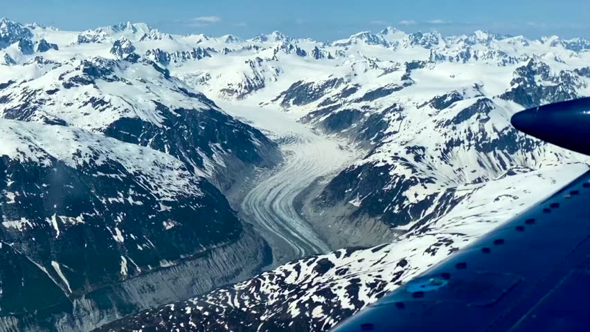 Glacier seen from small airplane in Lake Clark Pass, Alaska. Dark debris lines called lateral or medial moraines along the edges and down the center of glacier. 