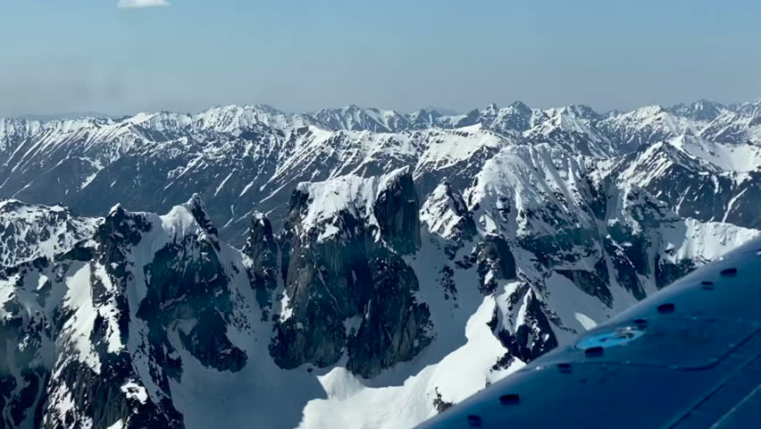 Beechcraft Bonanza airplane wingtip flies over Lake Clark Pass in Alaska. Mount Redoubt in the background. Small aircraft are only way to see many areas of Alaska.