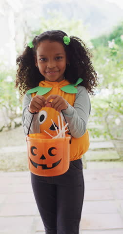 Vertical video portrait of smiling african american girl trick or treating in halloween costume. Childhood, tradition and halloween concept digitally generated video.