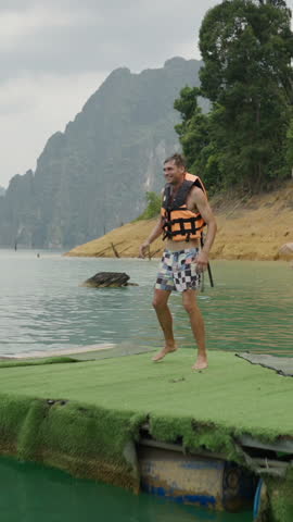 Caucasian couple jump into lake water