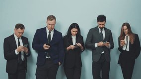 Group of professionals engrossed in their smartphones against a plain wall, each absorbed in their own mobile world. Modern connectivity, corporate lifestyle and mobile addiction in workplace - Powered by Shutterstock - Get 15% off with code: PIKWIZARD15