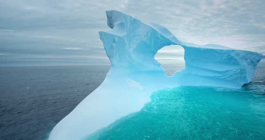 Large iceberg with melted hole floating arctic ocean. Big glacier unusual shape drift blue water. Ice cave glacial formation. Ecology, melting ice, climate change, global warming. Panorama shot 360