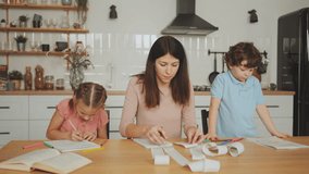 Single mother manages her finances by reviewing receipts, expenses and checks, trying to give her son attention and overseeing daughter's homework in kitchen. Challenging balance of single parenthood - Powered by Shutterstock - Get 15% off with code: PIKWIZARD15