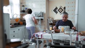 Happy senior retired couple eating lunch together, married elderly husband and wife enjoying meal, clinking glasses celebrating simple food inside humble quaint residential home - Powered by Shutterstock - Get 15% off with code: PIKWIZARD15