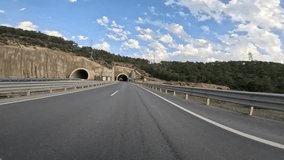 Car drives through tunnel, capturing tunnel, car point of view. Video shows darkness then emergence, highlighting tunnel, car point of view. Focuses on journey, tunnel, car point of view from inside