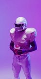 Vertical video of african american male american football player with neon purple lighting. Sport, movement, training and active lifestyle concept.