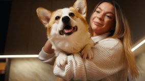 Admiration and cuddles: Young woman holds and showers love on her corgi at home