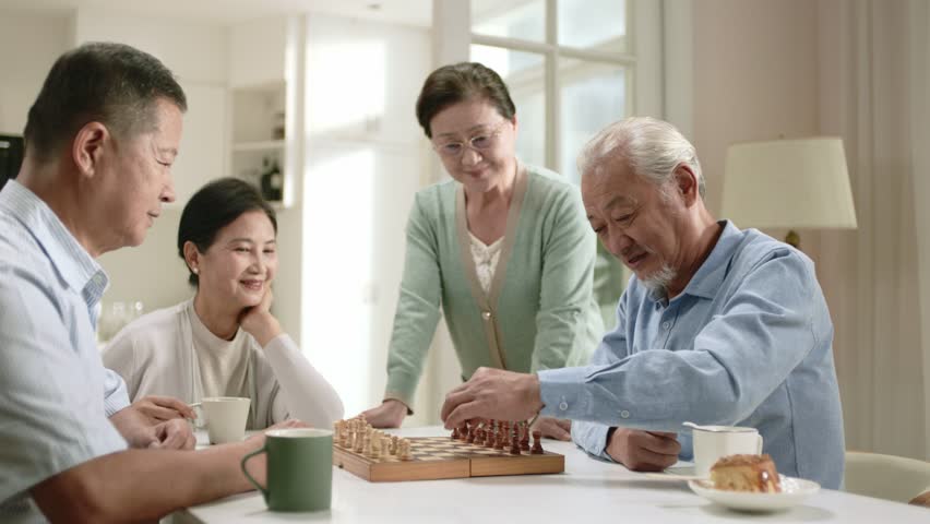 two happy senior asian couples gathering at home sitting at table playing chess - Powered by Shutterstock - Get 15% off with code: PIKWIZARD15