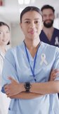 Vertical video of portrait of happy biracial female doctor with cancer ribbon. Global medicine, health, lifestyle and hospital concept.